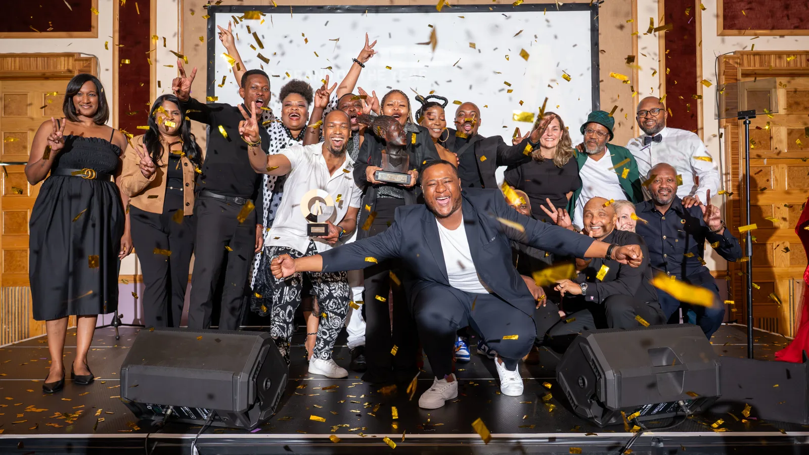 Large group of Assegai Awards 2025 winners celebrating on stage with gold confetti