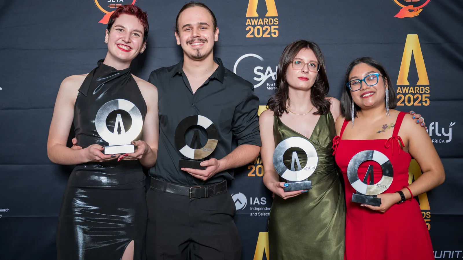 Guests posing with their Assegai Awards 2025 trophies at the event backdrop